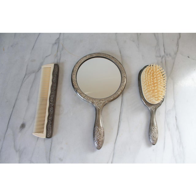 Vintage silver plated vanity set. Includes hand held mirror, brush and comb. No makers mark. Tarnishing.