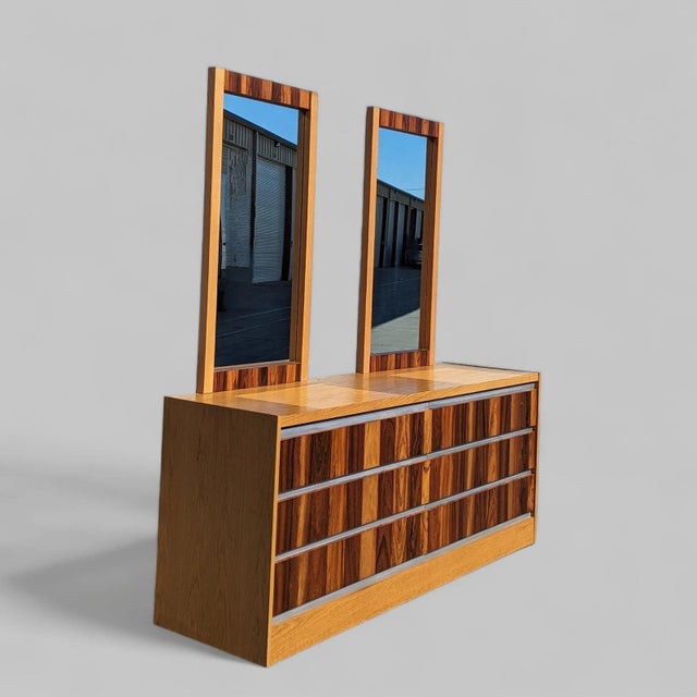 Mid-century lowboy dresser made in Canada with oak case construction, rosewood drawer fronts, chrome accents, and matching...