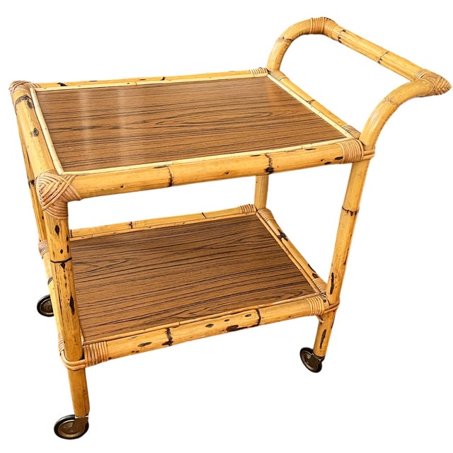 Chic 1960s drinks cart crafted in faux bamboo with hand-wrapped rattan joinery details and warm oak-grain laminate...