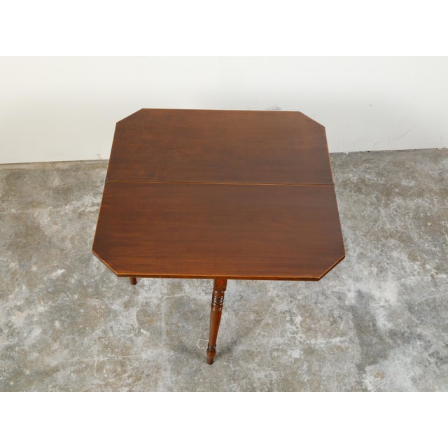 An English Regency period lift top console table from the early 19th century, with turned legs and elongated arrow feet....