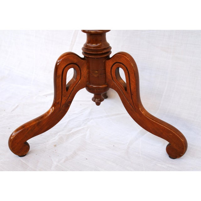 Antique coffee table made of mahogany, of English origin. Round table top with wavy edges, carved base rests on three feet...