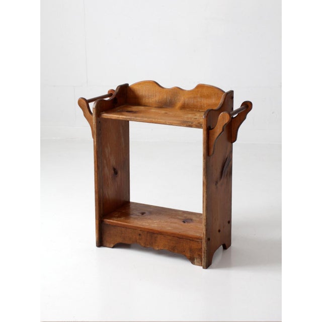 An antique pine washstand featuring a warm honey-brown finish, a scalloped backsplash, and decorative wooden towel bars...