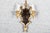 A pair of ornate gilt electric wall sconces with a scalloped, Gothic-inspired framed silhouette, shaped mirrored back...