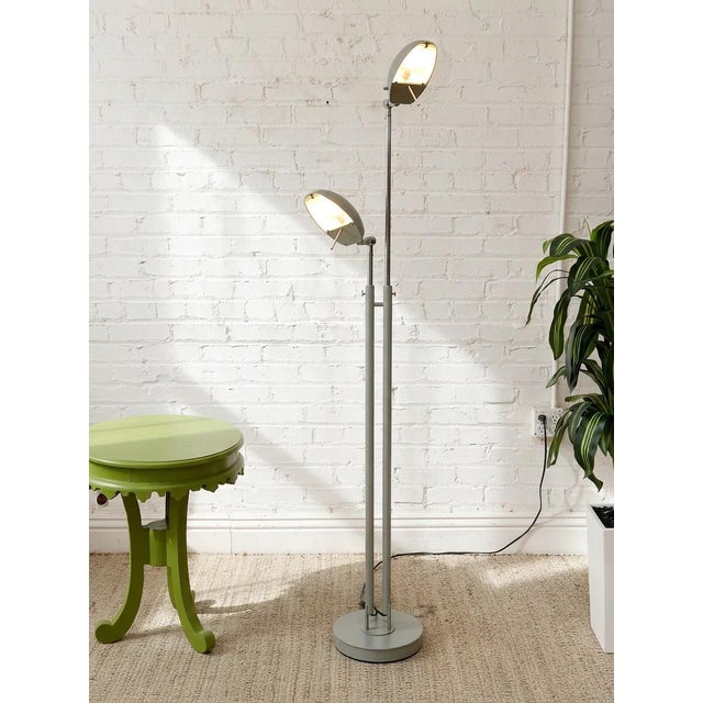 A sleek vintage floor lamp featuring two independently positioned dome shades set at different heights along a tall,...