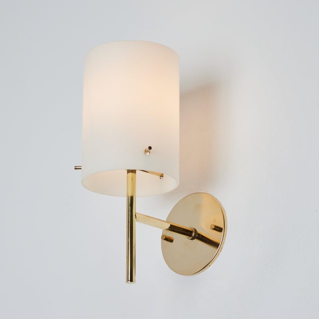 1950s Tito Agnoli brass & glass cylindrical wall lamp for O-Luce. Executed in opaline glass and patinated brass. An...