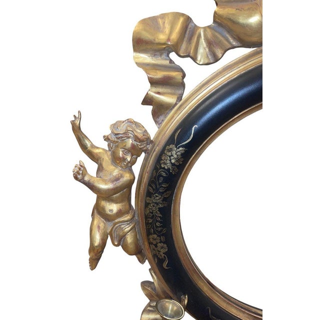 A striking 20th century Italian Rococo-style wall mirror crafted in carved wood with giltwood decoration and partial...