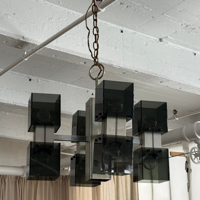This striking Mid-Century Modern chandelier features a bold architectural silhouette defined by a central chrome pillar...