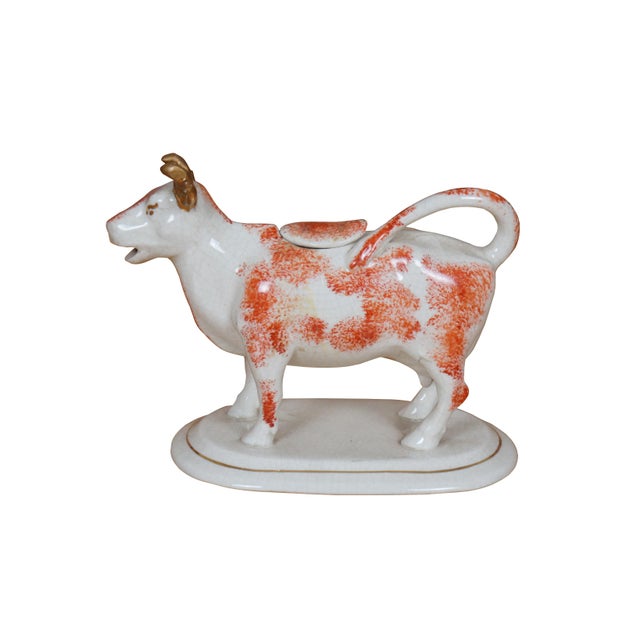 Antique 19th century Staffordshire porcelain cream pitcher in the shape of a red and white cow standing on an oval base....
