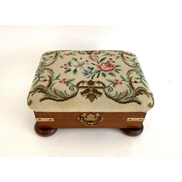 Beautiful wool needlepoint upholstered stool with mahogany base, brass fixtures and resting on four bun feet. The original...