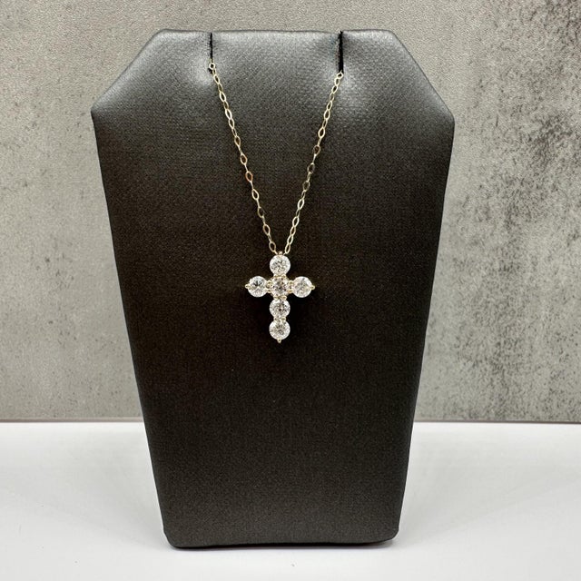 This diamond cross necklace is crafted in 14kt yellow gold and features a timeless cross pendant adorned with 1.10 carats...