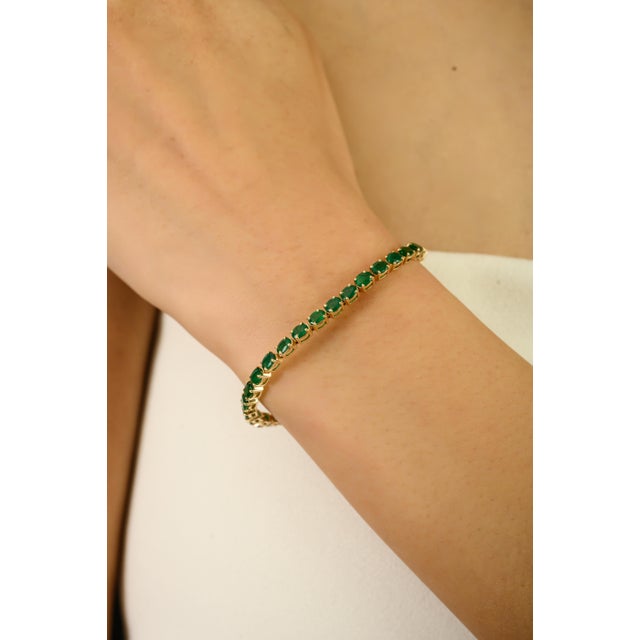 This elegant tennis bracelet showcases a continuous line of natural oval-cut Zambian emeralds totaling 5.41 carats, set in...