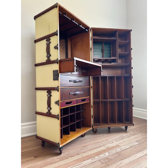 Exclusive bar cabinet in burgundy that is easy to move. Made in the style of turn-of-the-century travel trunks. Solid...