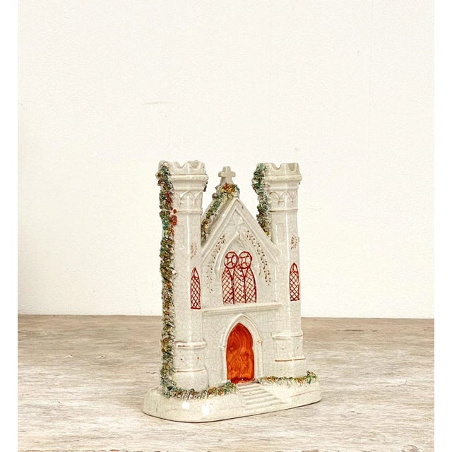 An English Staffordshire church with an orange front door and 2 towers flanking the doorway, circa 1880.