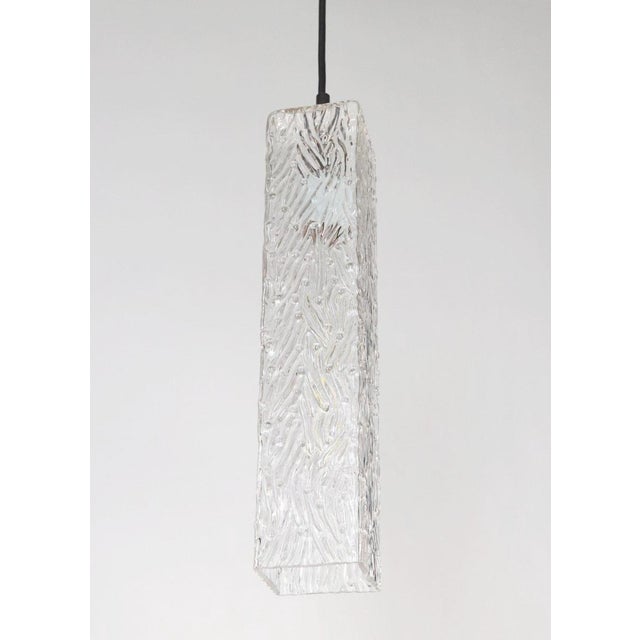 This Modern style pendant light is made of a square clear Murano wave glass shade paired with a black cord fitter. The...