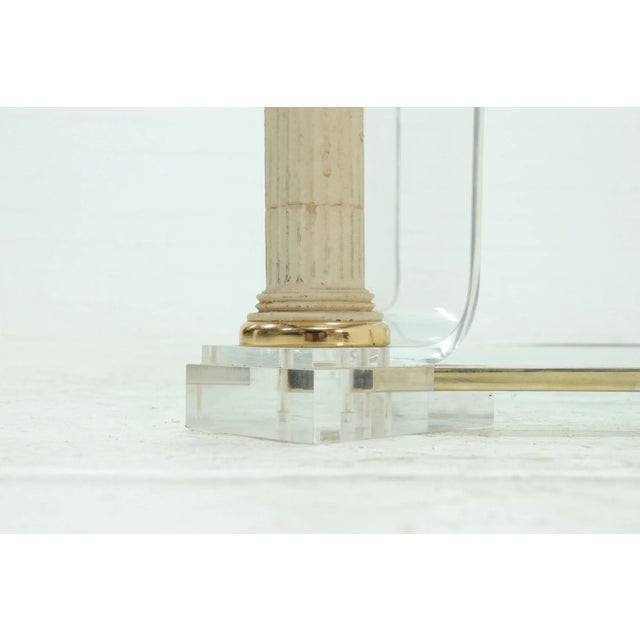 Two tier coffee table designed in the 1980s. The table features a heavy acrylic glass frame with poly stone pedestals on...