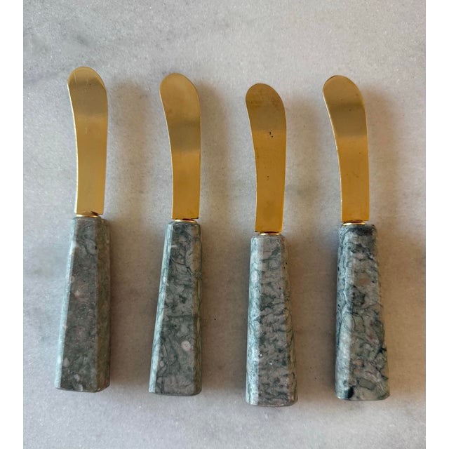 Set of 4 vintage serving spreader knives with marble stone handles and golden metal blades.