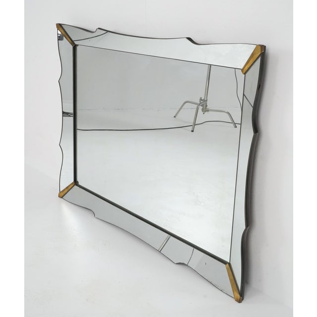 1960s Mid Century style wall mirror with a beveled, scalloped edge and brass plated steel corner accents. No mounting...