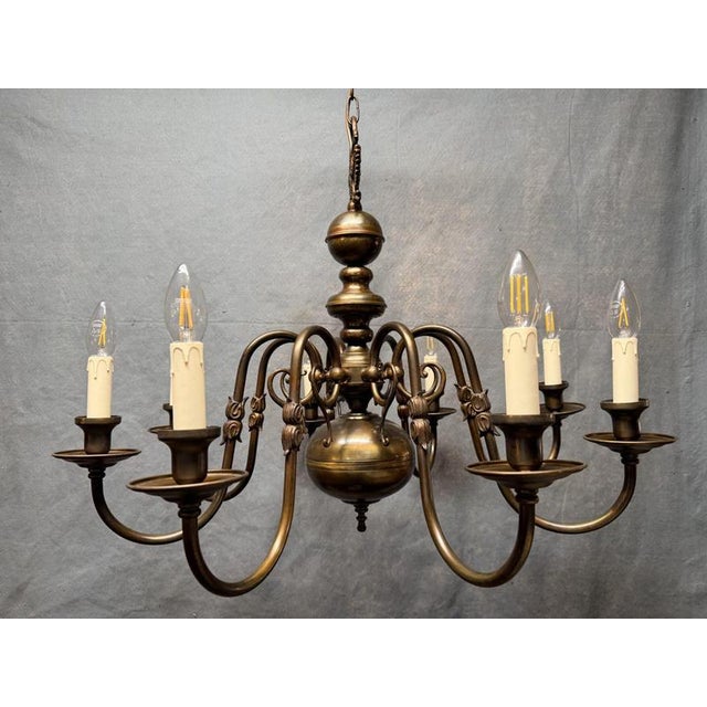 A very good antique Flemish chandelier in brass, with eight sweeping branches radiating from a central baluster column....