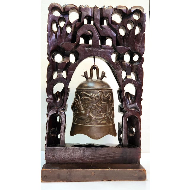 Vintage Asian Bell with dragon design on carved wood stand. Pagoda or temple-like structure carved at top of stand and...