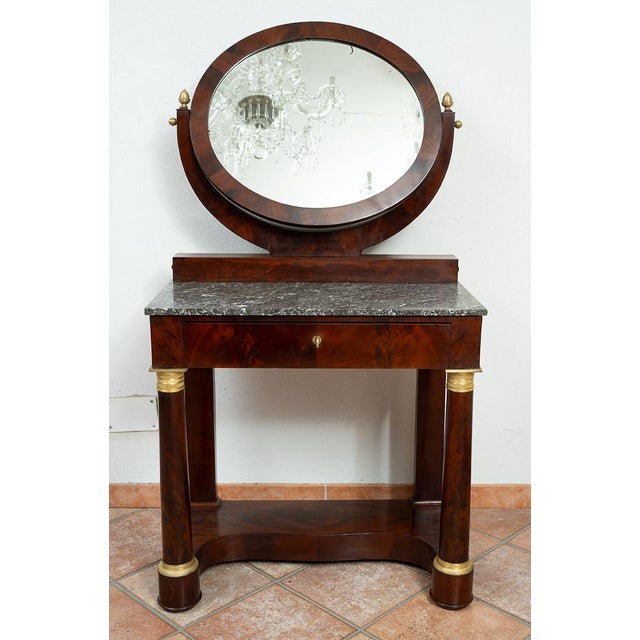 Antique mahogany dressing table with gilded bronze inserts from the early 19th century. The lower part of the main façade...