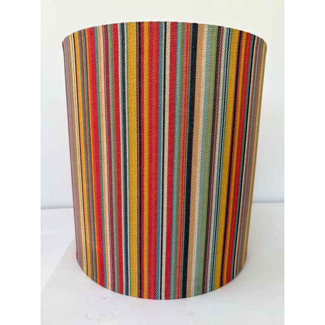 Vibrant and cheerful, this vintage cylindrical lampshade from the 1970s features a woven multicolor striped fabric in bold...