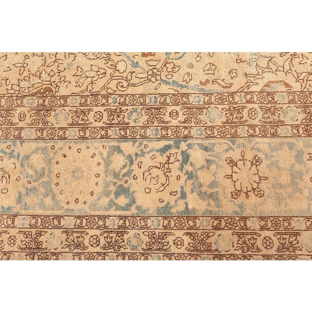 An early 20th century Persian carpet, the abrashed camel field with an allover lattice of blue vinery and polychrome...