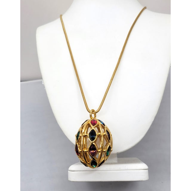 This is part of Chairish’s Costume Jewelry assortment. Early 1990s goldtone egg shaped openwork pendant with marquise...
