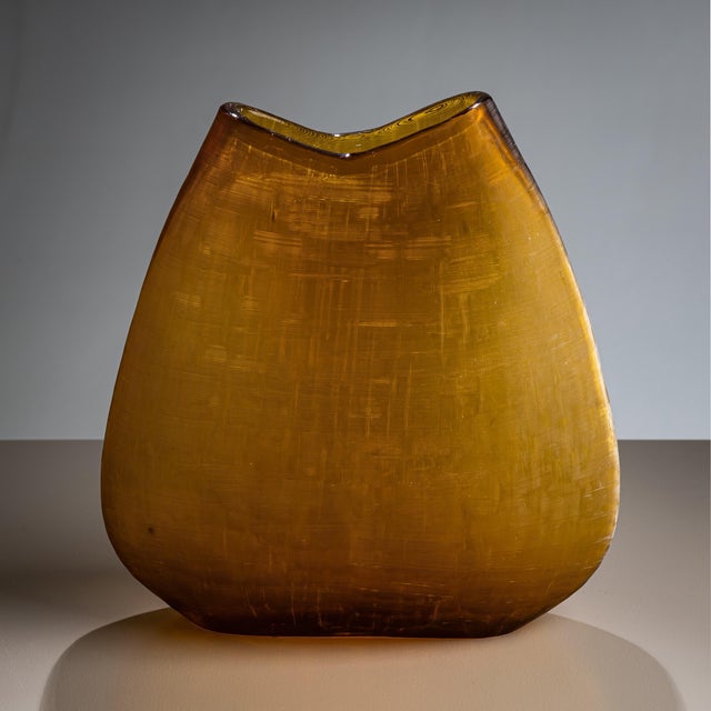 Large vase in amber-colored glass with a finely textured surface and gently flattened, bulbous form.