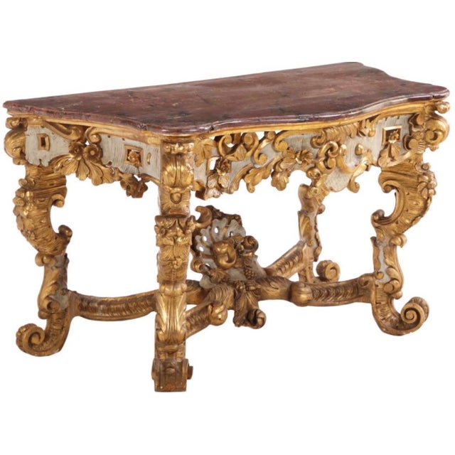 Early nineteenth century Italian large scale painted giltwood console table with faux marble top and ornate carvings....