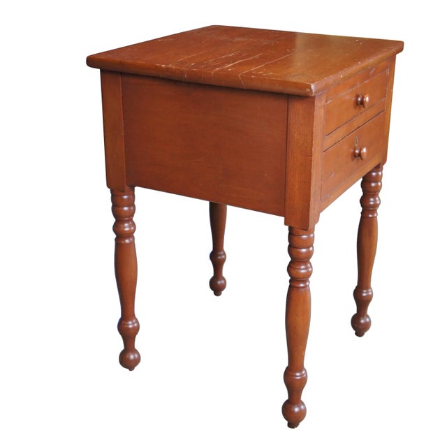 Antique Early American 19th century side table. Made of cherry featuring rectangular form with two dovetailed drawers over...