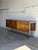 An architectural low-slung credenza configuration features sliding cabinet doors that glide smoothly to reveal integrated...
