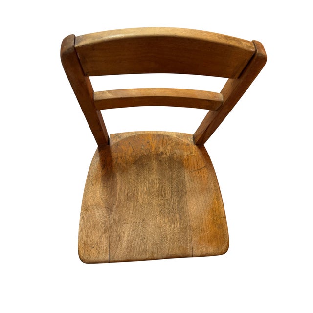 Child-size wooden school chair with a saddle-style seat. The underside is ink-stamped Allen Chair Corp., West Concord,...