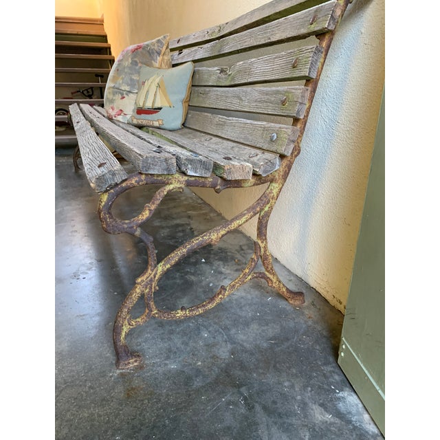 This vintage French-style garden bench features cast iron legs designed to resemble natural tree branches or snakes,...