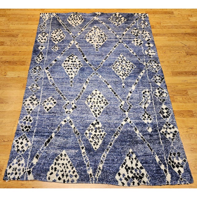 A vintage Mid-Century Moroccan room size rug was hand-woven in an all-over geometric pattern. The rug's main field is a...