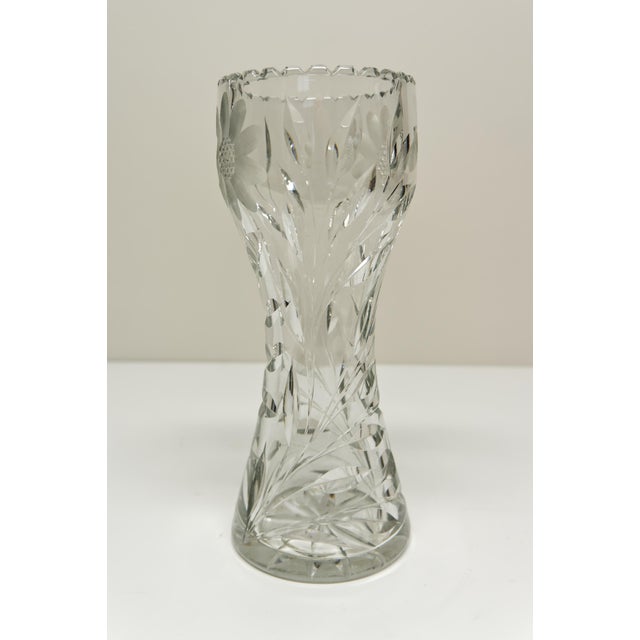 A clear cut glass corset shaped vase with scalloped rim featuring a daisy floral design and a starburst on the bottom....