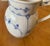 Cobalt blue floral motifs on a finely ribbed porcelain body; arched handle with a stylized snail shell accent at the top...