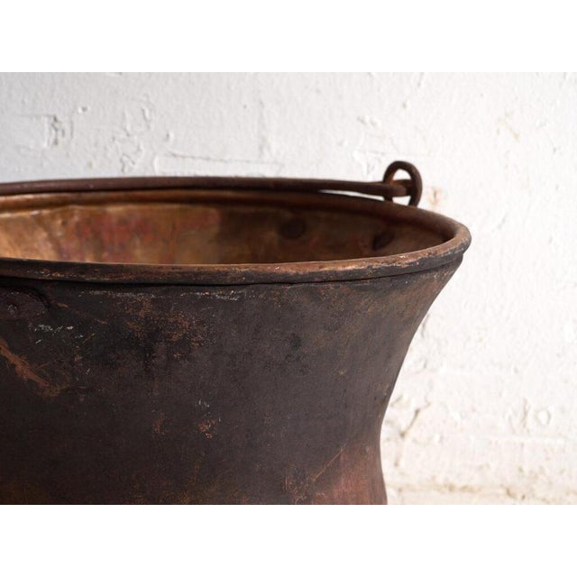 This antique copper cauldron is a kitchen vessel of hammered copper with an iron handle. It originates from central...