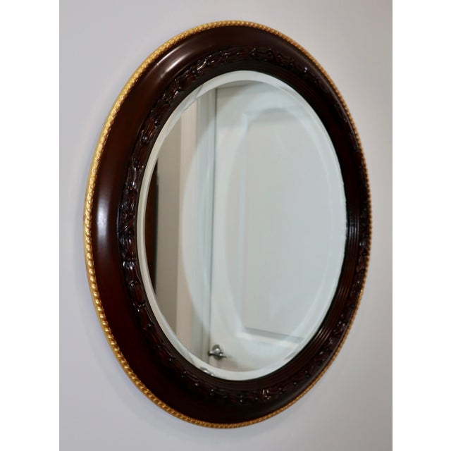 1980's Edwardian style walnut and gold leaf round wall mirror by William Switzer, in vintage condition with minor wear and...