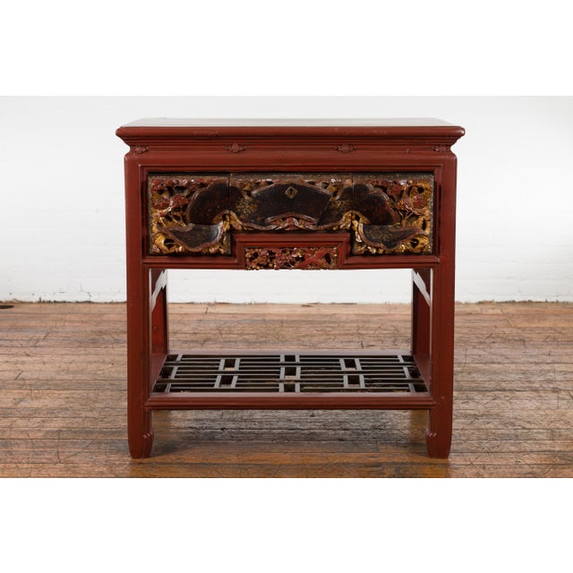 A Chinese red lacquered console table from the 20th century made with 19th century carved pieces, with very unusual hand...
