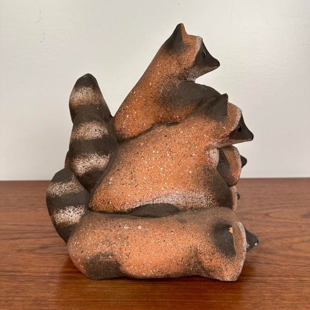Ceramic sculpture by Dane Burr featuring 5 raccoons piled on each other. There is no makers mark on this piece.