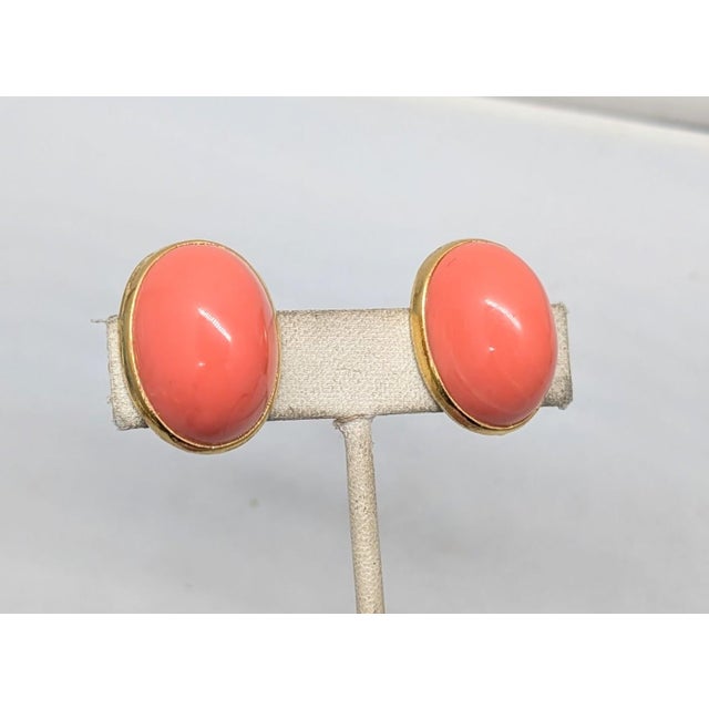 1970s or 1980s oval goldtone cabochon faux-coral clip earrings. Marked "ALEXIS © KIRK" in a cartouche on the backs....