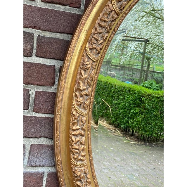 A beautiful vintage French Louis XVI style oval wall mirror dating from the 1970s, handcrafted from solid beechwood with...