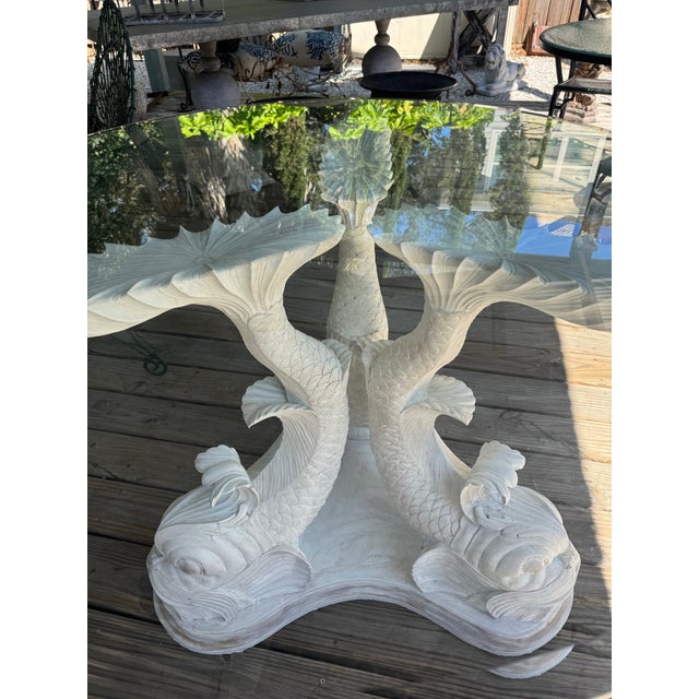 Vintage painted carved wood dolphin pedestal table. Distressed white finish with muted gold accents on the base and...