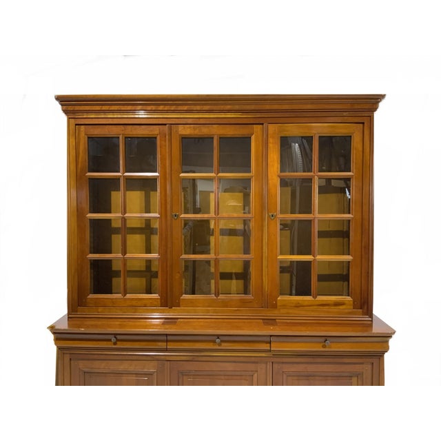 A Georgian style cherry wood bookcase or china cabinet with warm honey tones, molded cornice top, two-piece construction...