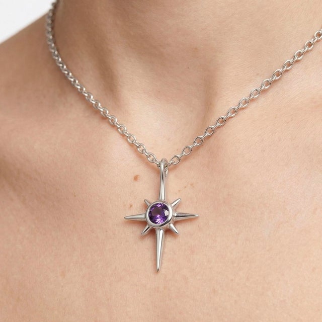 This striking pendant features a delicate Amethyst gemstone at its center, beautifully framed within a contemporary star-...