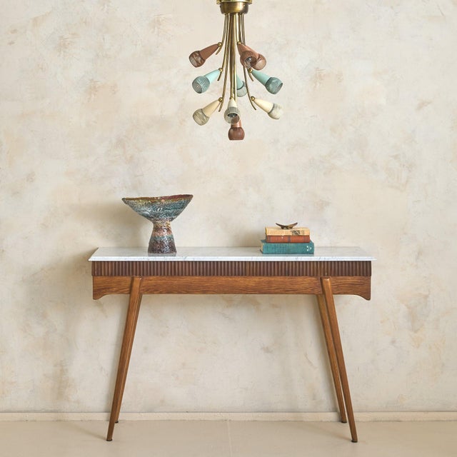 A 1950s Italian console table, defined by its fluted wood façade. Gently curved vertical detailing creates a rhythmic...
