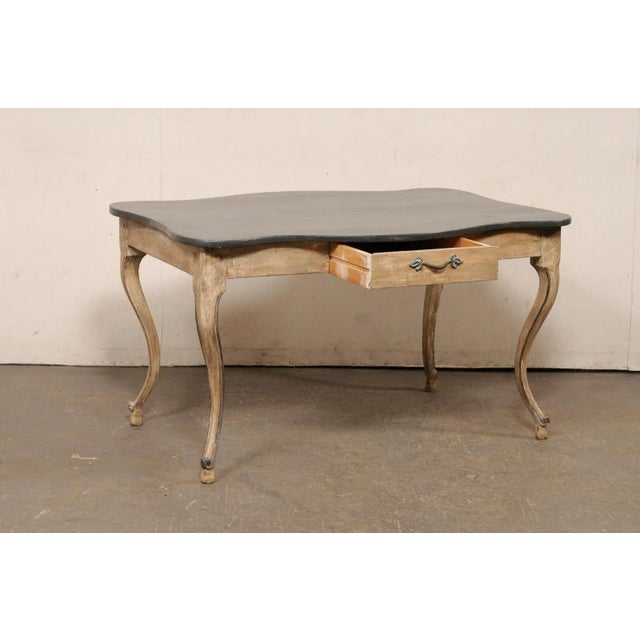 A French carved and painted wood table (or desk), with shapely legs and top edges, from the 19th century. This antique...