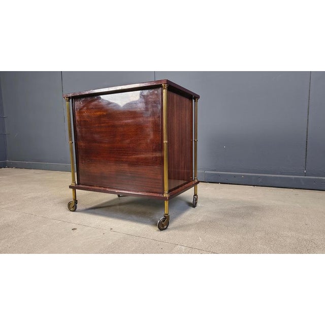 Mid century dry bar with a mahogany casing, patinated brass hardware and picture of sailships. Very stylish mobile bar...
