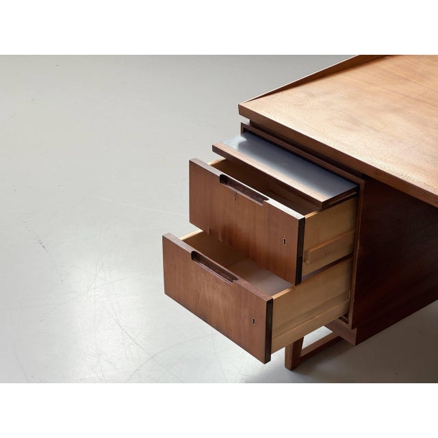 An elegant mid-century modern desk with clean lines and a functional design from the 1960s. The body is veneered in warm...