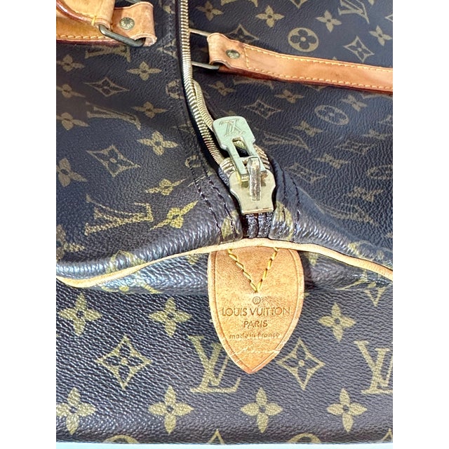A Louis Vuitton logo-printed Louis Vuitton Keepall 55 with leather trim with bring a touch of heritage luxury wherever you...